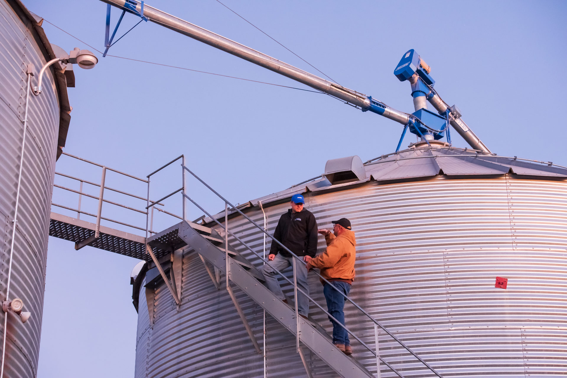 Shivvers176 farmers standing on stairs next to a grain bin | Shivvers